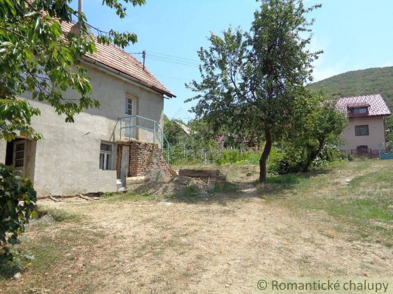 Ein Einfamilienhaus in Šiatorská Bukovinka mit Garten und Bäumen unter blauem Himmel.
