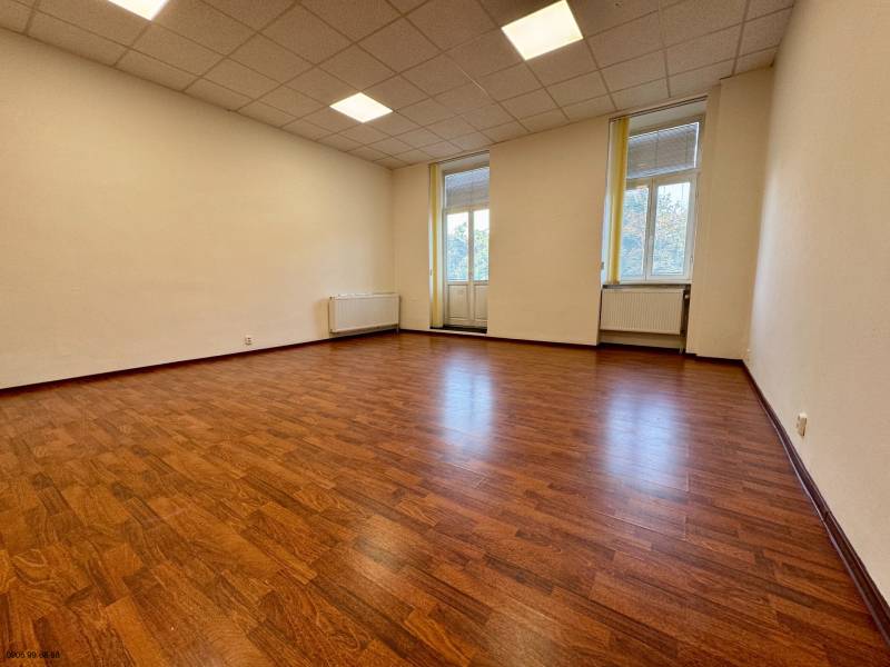 Ein leeres Büro mit Holzboden und großen Fenstern.