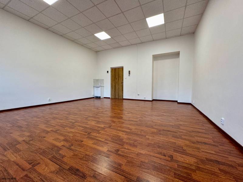 Ein Büro mit einem Boden in Holzoptik, weißen Wänden und einer abgehängten Decke.