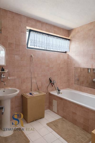 Badezimmer in einem Einfamilienhaus mit Fliesen und Badewanne; ein Korb aus Weide neben dem Waschbecken.