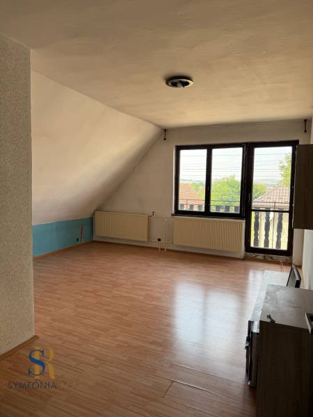 Ein Zimmer in einem Einfamilienhaus mit einem Holzboden und großen Fenstern.