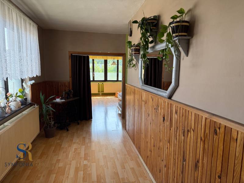 Ein Flur in einem Einfamilienhaus mit einem Boden in Holzoptik und Zimmerpflanzen an der Wand.