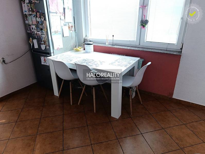 Küche einer 2-Zimmer-Wohnung mit Esstisch, weißen Stühlen und Fenster.