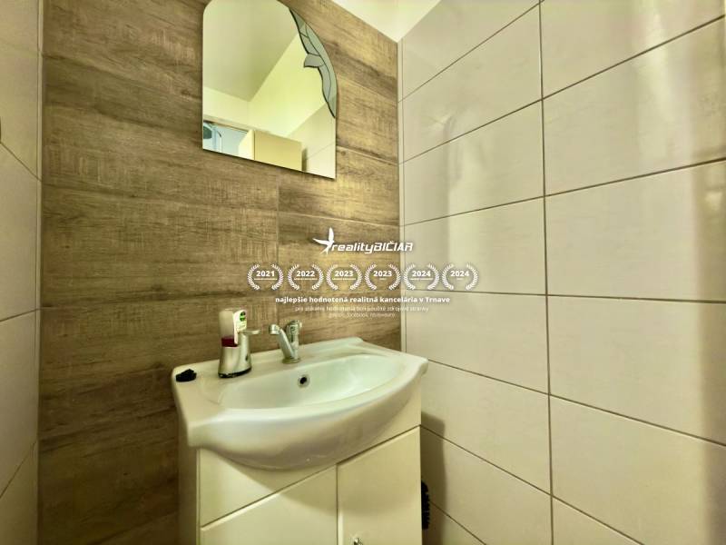 Badezimmer in einer 2-Zimmer-Wohnung mit Waschbecken und Spiegel, Wand mit Holzdekor.