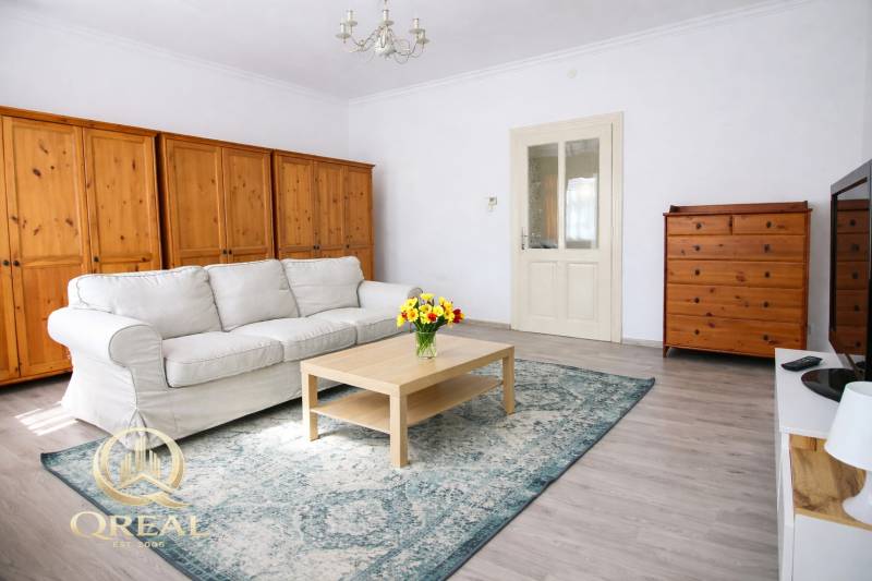 Helles Wohnzimmer mit Sofa, Holzmöbeln und Boden in Holzoptik.