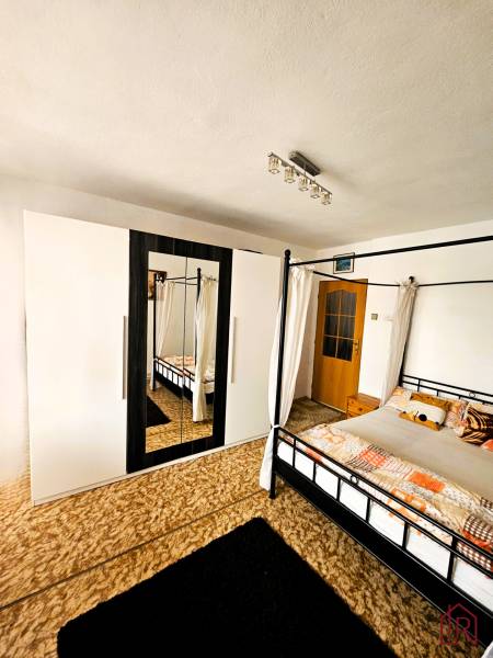 Ein Schlafzimmer in einem Einfamilienhaus mit einem Bett, einem Teppich und einem Schrank mit Spiegel.