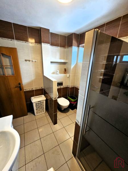 Badezimmer in einem Einfamilienhaus mit Fliesen, Dusche und Toilette.