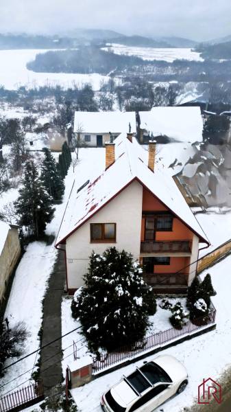 Ein Einfamilienhaus in Kameňany, bedeckt mit Schnee, mit Blick auf verschneite Felder und Hügel.