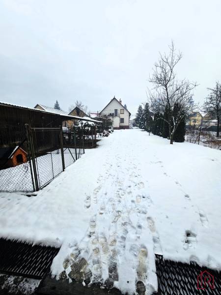 Ein Einfamilienhaus in Kameňany mit einem schneebedeckten Hof, umgeben von einem Garten und Bäumen.