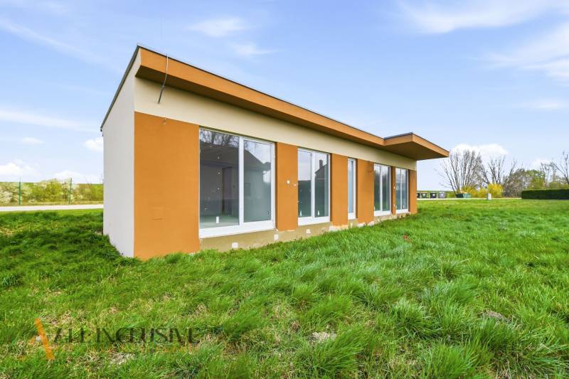 Ein Ferienhaus in Vojka nad Dunajom mit einer Umgebung aus grünem Gras und großen Fenstern.