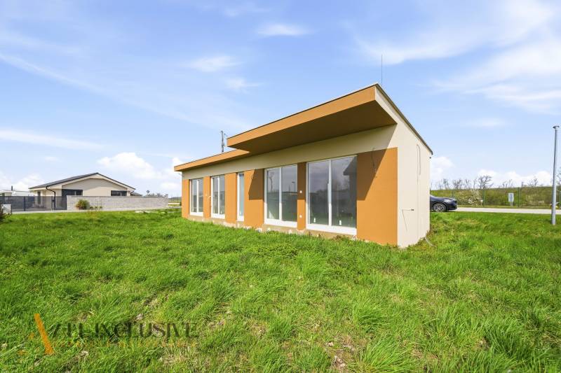 Ein Ferienhaus in Vojka nad Dunajom mit Rasen und verglasten Wänden.