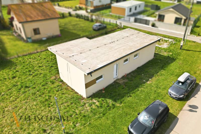 Ein Ferienhaus in Vojka nad Dunajom mit Flachdach und geparkten Autos auf der Rasenfläche.