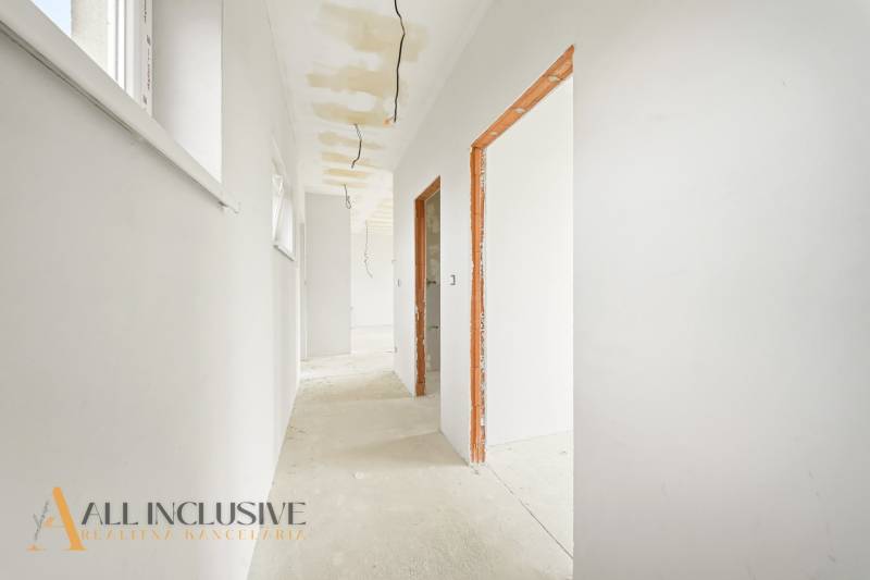 Ein heller Flur in einer Hütte mit rohem Boden, weißen Wänden, sichtbaren Kabeln.