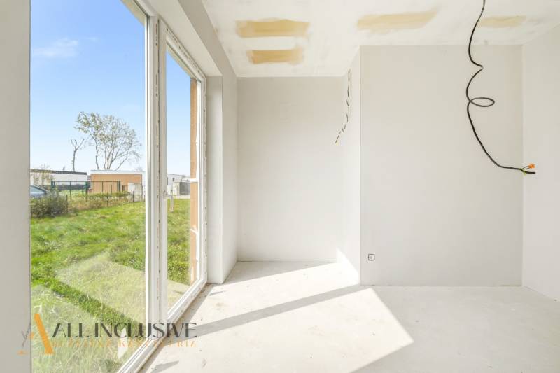 Interieur einer Hütte mit großen Fenstern und Blick auf eine Rasenfläche.