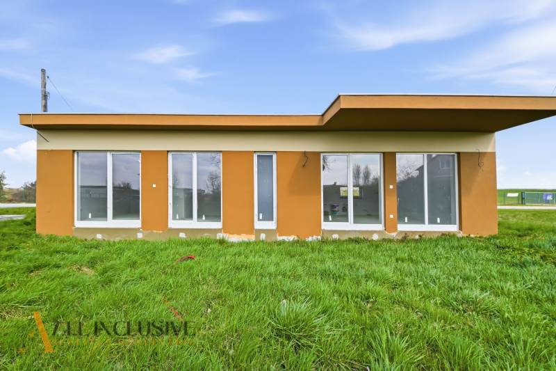 Ein Ferienhaus in Vojka nad Dunajom mit großen Fenstern und Flachdach, umgeben von einer Rasenfläche.