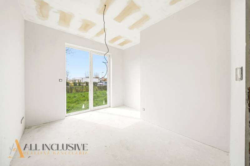 Ein leerer Innenraum einer Hütte mit einem großen Fenster und Blick in den Garten.