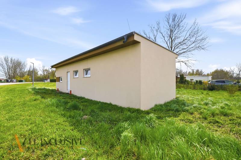 Eine Hütte in Vojka nad Dunajom, umgeben von Grün, neben einer Asphaltstraße.