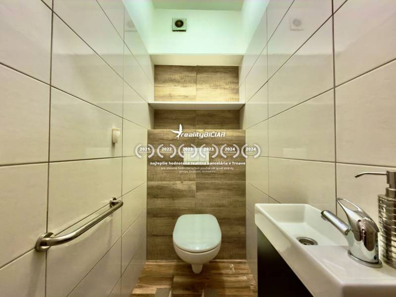Badezimmer in einer 2-Zimmer-Wohnung mit Holzboden und weißen Fliesen.