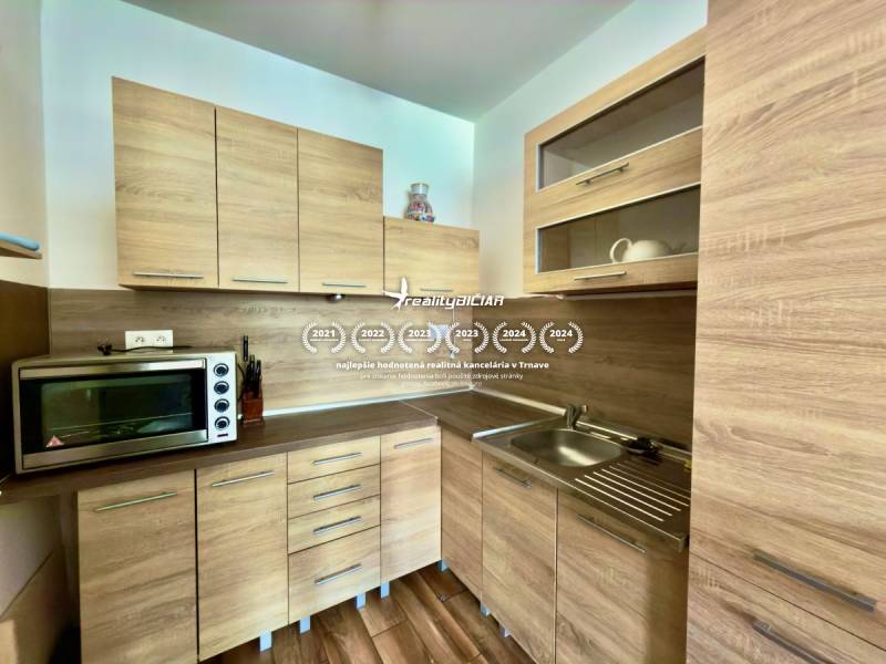 Küche mit Einbauschränken und Boden in Holzoptik in einer Zweizimmerwohnung.