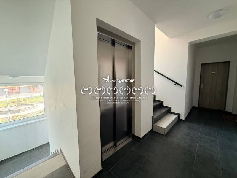 Flur mit Aufzug und Treppenhaus in einer 2-Zimmer-Wohnung, Boden mit Holzdekor.