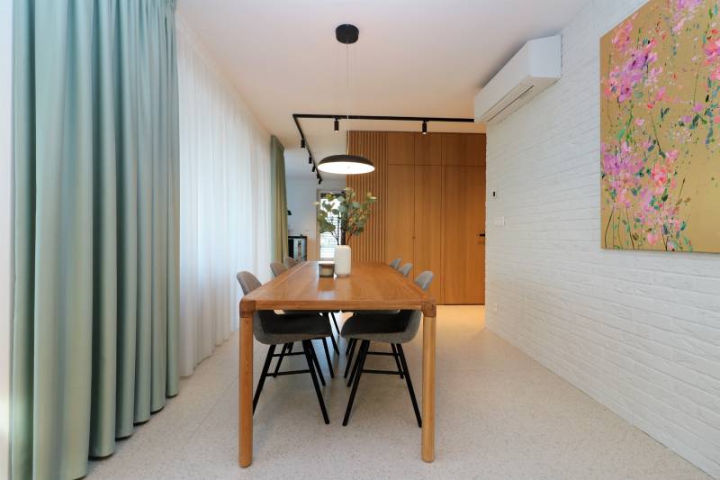 Esszimmer in einer 4-Zimmer-Wohnung mit Holztisch und dekorativer Wandmalerei.