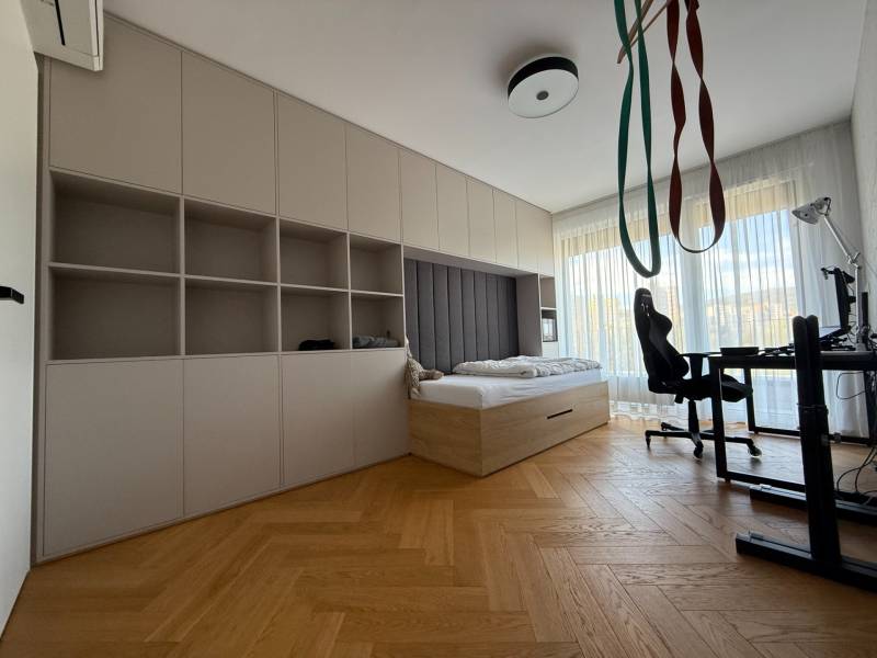 Ein Zimmer in einer 4-Zimmer-Wohnung mit einem Bett, einem Tisch und einem Boden in Holzoptik.