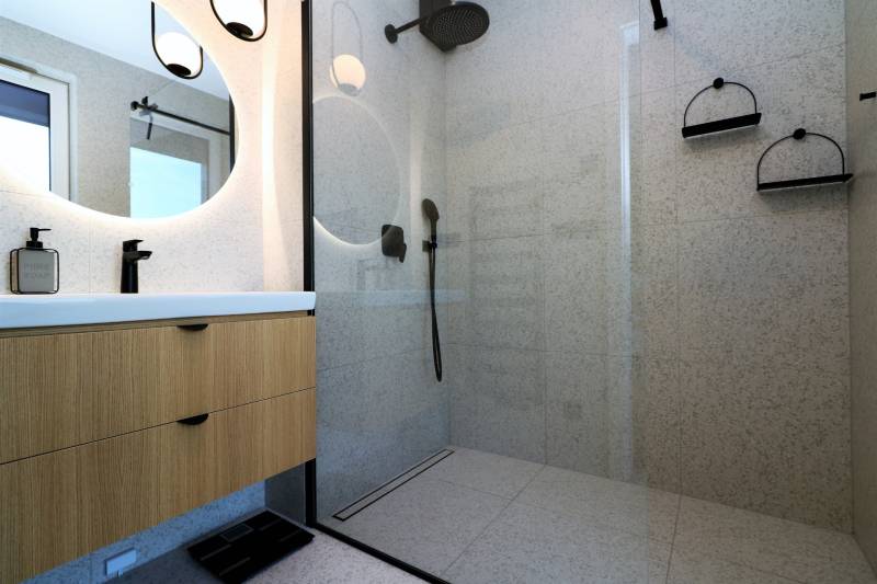 Duschkabine mit Glastüren und Waschbecken in einer 4-Zimmer-Wohnung.