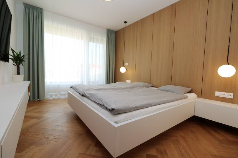 Schlafzimmer in einer 4-Zimmer-Wohnung mit Holzboden, weißen Möbeln und einem großen Fenster.