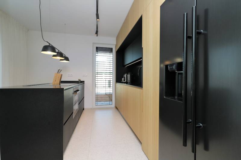 Küche in einer 4-Zimmer-Wohnung mit schwarzer Küchenzeile und Holzschränken.