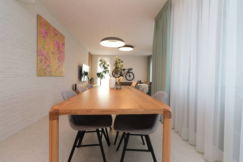 Esszimmer mit großem Holztisch, Stühlen und Vorhängen in einer Vierzimmerwohnung.