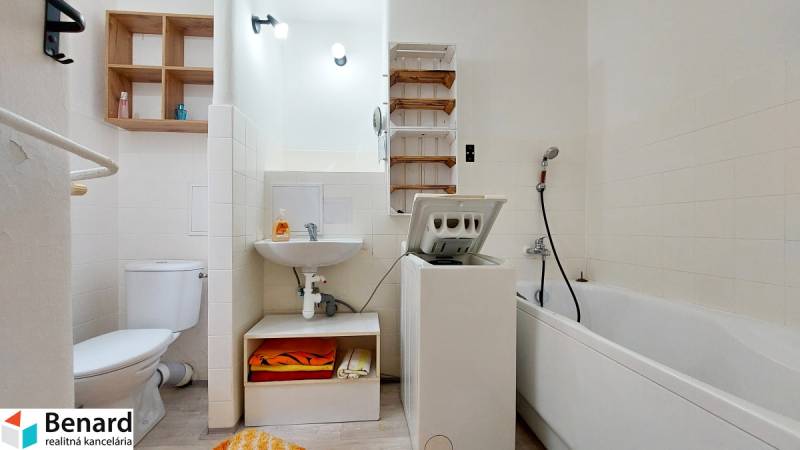 Badezimmer in einer 2-Zimmer-Wohnung mit Dusche, Waschmaschine, WC und Waschbecken.