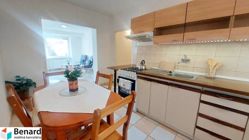 Küche in einer 2-Zimmer-Wohnung mit Sitzgelegenheit, hellem Boden und Esstisch.