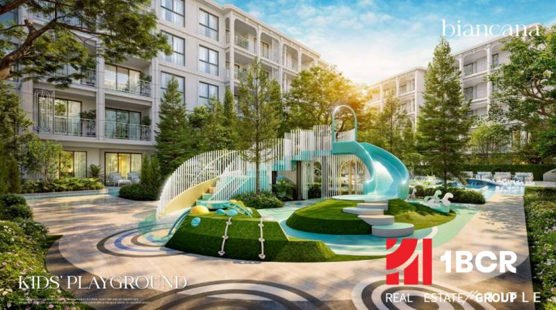 Spielplatz bei einem Wohnungsbauprojekt in Phuket mit großer Rutsche und viel Grün.