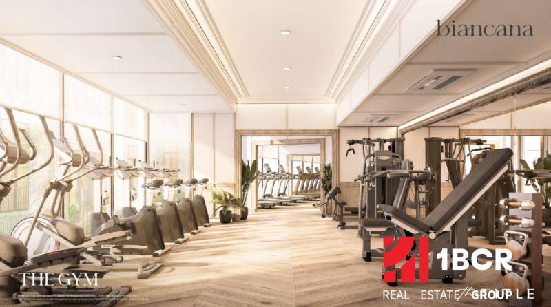 Ein Innen-Fitnessstudio mit Holzdekorboden und Fitnessgeräten in einem Wohnungsbau.