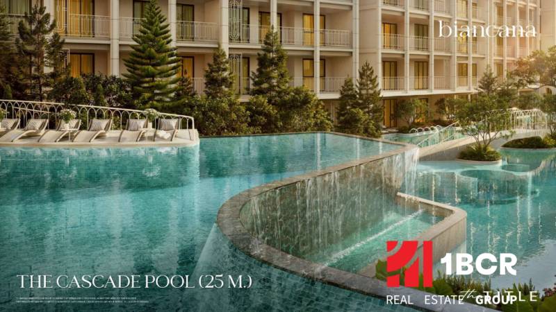 Ein Pool mit Kaskaden beim Bau von Wohnungen in Phuket mit Liegestühlen und Grünflächen.