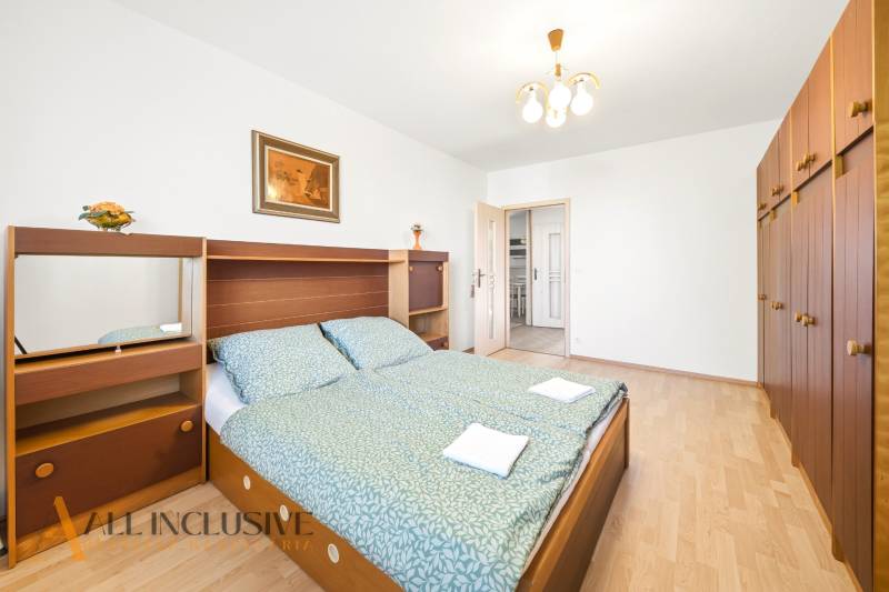 Schlafzimmer in einem Einfamilienhaus mit großem Bett, Schrank und Boden mit Holzdekor.