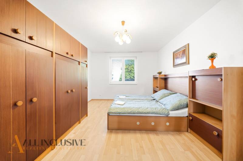 Schlafzimmer in einem Einfamilienhaus mit Holzboden, Stauraum und Bett.
