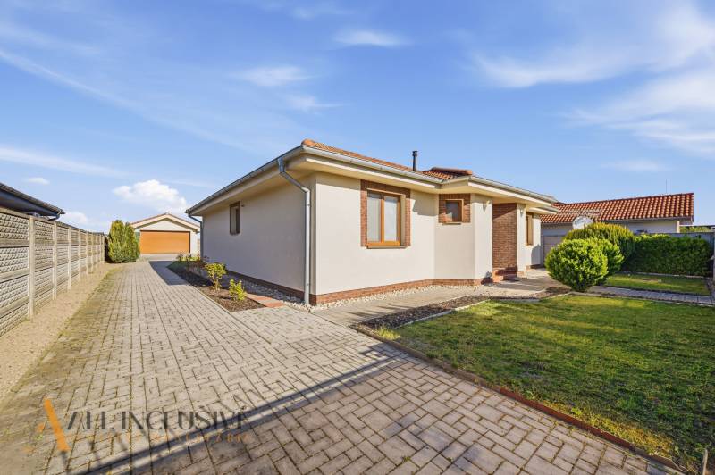 Ein Einfamilienhaus in Kútniky mit einem gepflasterten Gehweg und einem gepflegten Garten.