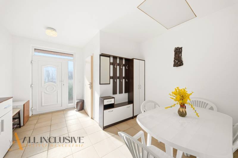 Innenraum eines Einfamilienhauses mit weißem Tisch, Plastikstühlen und einer Garderobenwand.