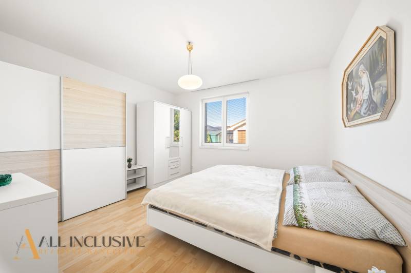 Schlafzimmer in einem Einfamilienhaus mit Holzboden, weißen Möbeln und einem Bild.