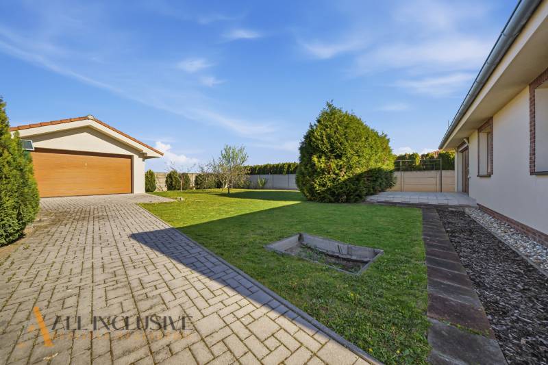 Einfamilienhaus in Kútniky mit Garage, Rasen und befestigter Zufahrtsstraße.