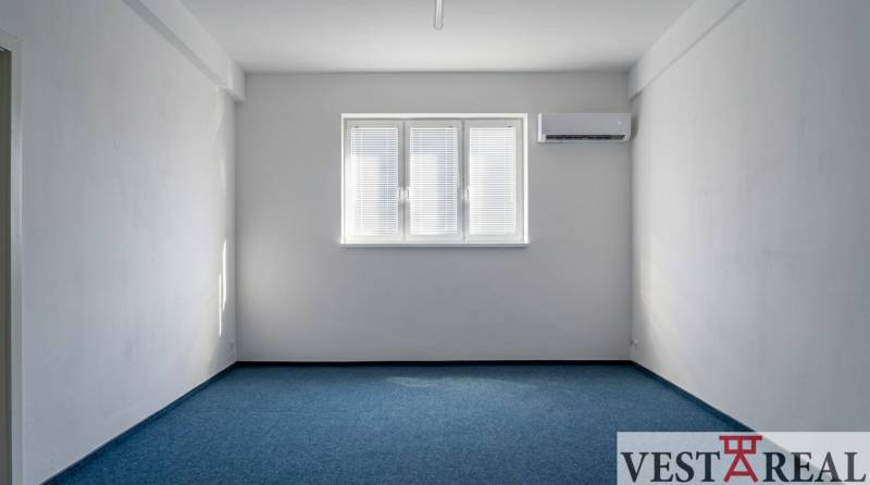 Büros mit blauem Teppichboden, weißen Wänden und Klimaanlage.