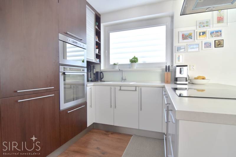 Küche in einer 3-Zimmer-Wohnung mit Holzboden und großem Fenster.