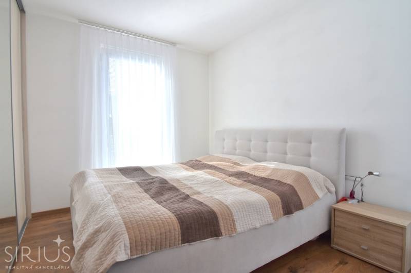 Schlafzimmer mit Bett und Nachttisch in einer 3-Zimmer-Wohnung, Boden mit Holzdekor.