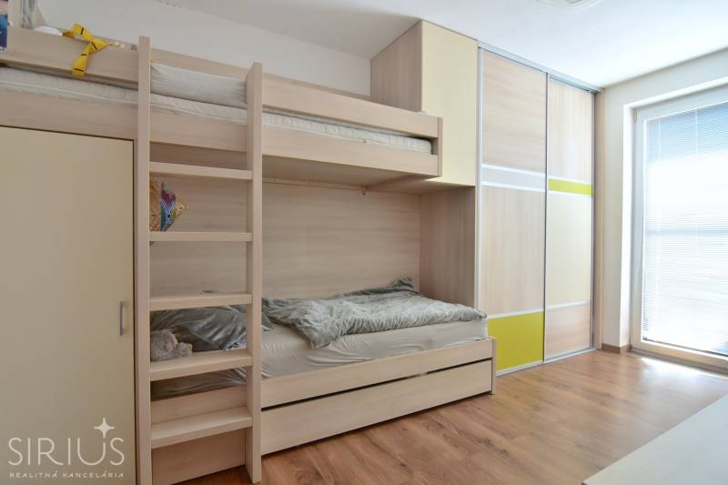 Etagenbett und Einbauschrank in einem Zimmer mit Holzboden.