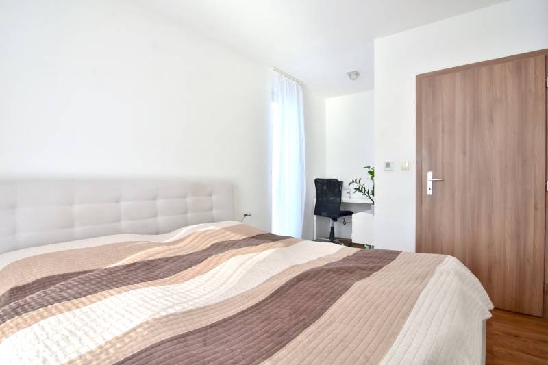 Helles Schlafzimmer mit Bett, Schreibtisch und Boden in Holzoptik in einer 3-Zimmer-Wohnung.