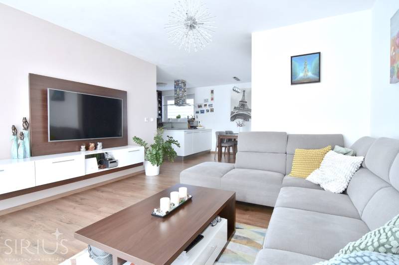 Wohnzimmer in einer 3-Zimmer-Wohnung mit Holzboden und grauem Sofa.