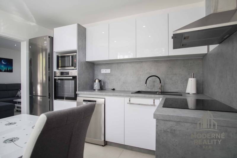 Küche in einer 2-Zimmer-Wohnung mit Edelstahlgeräten und grauer Arbeitsplatte.