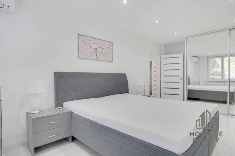 Helles Schlafzimmer mit großem Bett und Kleiderschrank in einer 2-Zimmer-Wohnung.