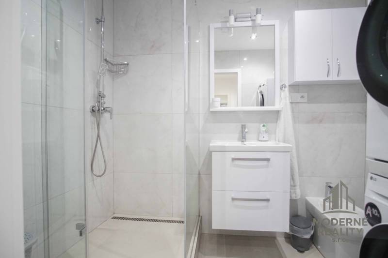 Badezimmer in einer 2-Zimmer-Wohnung mit moderner Duschkabine und weißem Waschbecken.